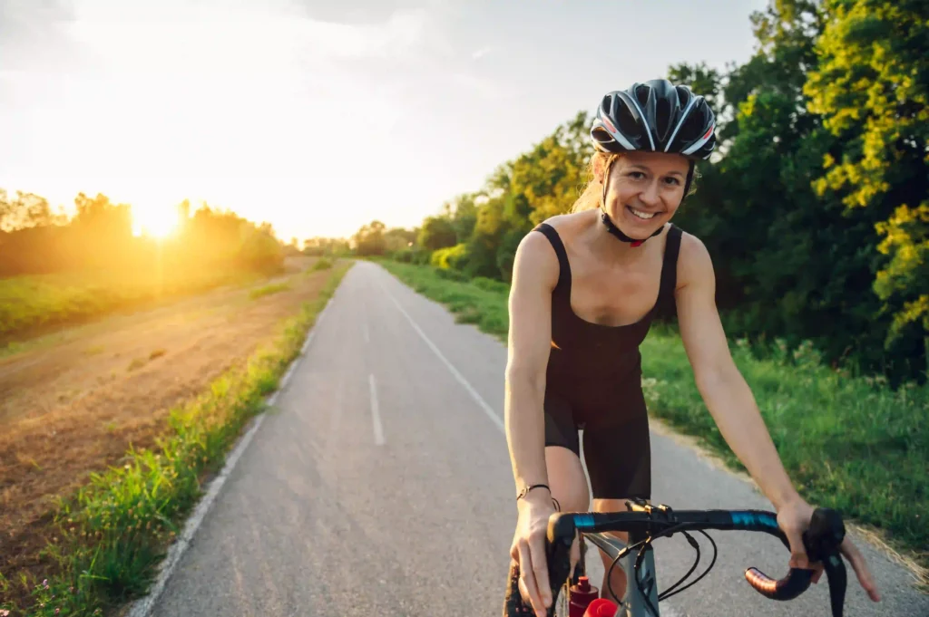 Sporty woman riding a bicycle in the nature while wearing a protective gear